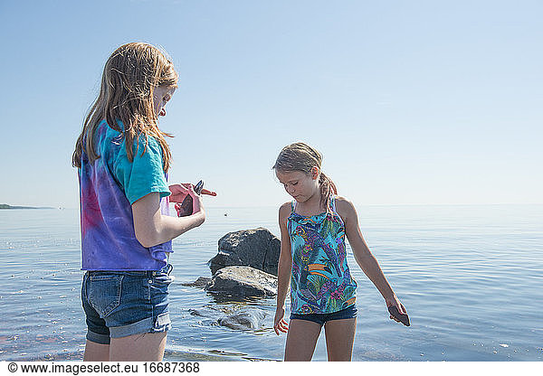 Two Young Girls Exploring Rocky Shoreline