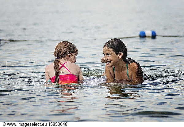 Two Young Girls in Swimsuits Playing in a Lake