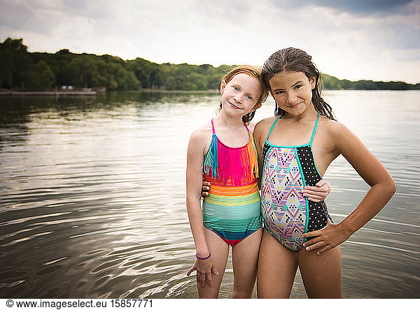 Two Young Girls in Swimsuits Standing by a Lake