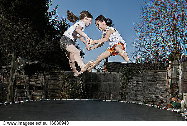 two young girls jumping on trampoline in Woking - England