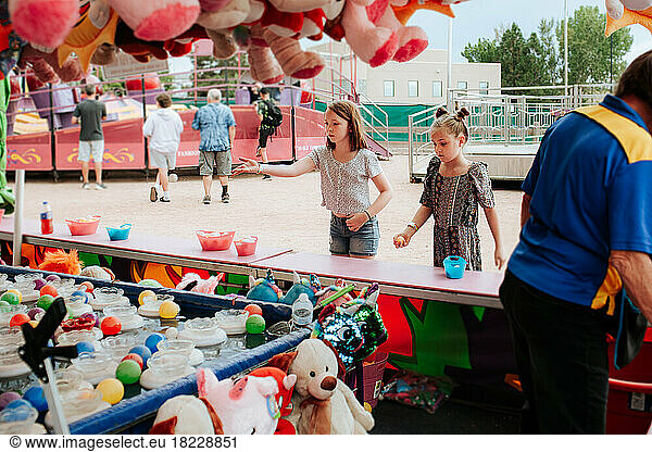 Two young girls playing a carnival game