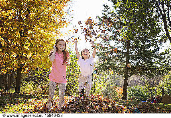 Two Young Girls Playing in Fall Leaves
