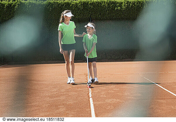 Two young girls preparing tennis court  Bavaria  Germany
