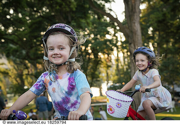 Two young girls ride bikes at sunset