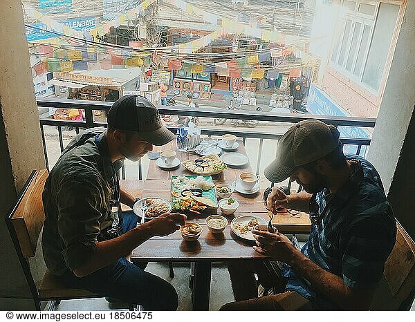 Two young men eating colorful meal on rooftop in Asia