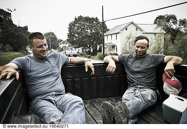 Two young men enjoy a cool breeze on back of the truck after working the field in Keymar  Maryland.