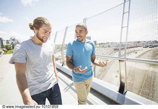 Two young men walking along a bridge.