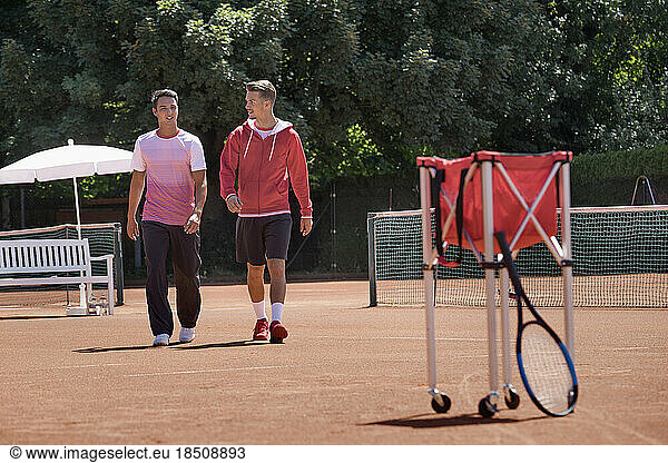 Two young men walking on tennis court  Bavaria  Germany