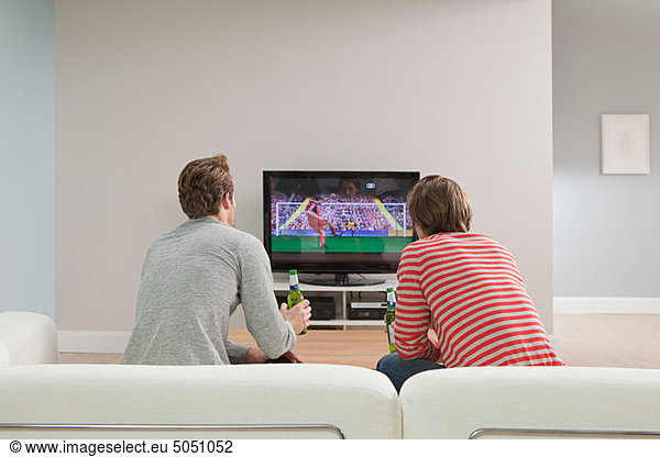 Two young men watching football on television