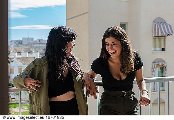 Two young women are having fun on a balcony of her house