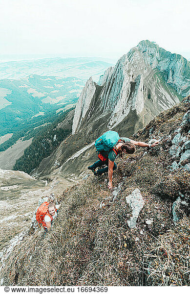 Two young women climbing steep terrain in front of steep mountains