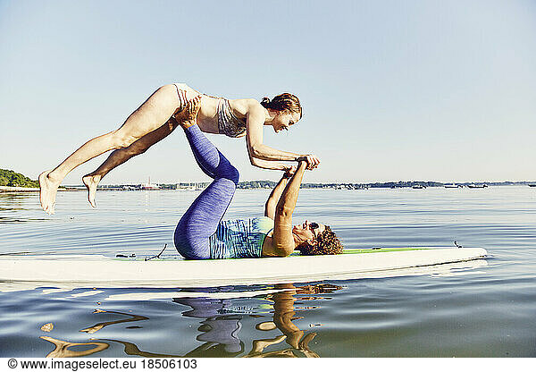 Two young women doing yoga on a standup paddle board
