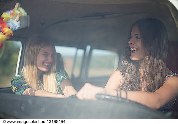 Two young women in campervan  laughing