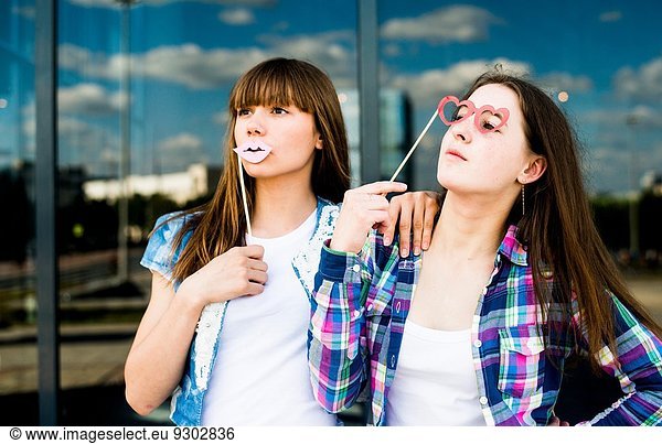 Two young women looking up with lip and spectacles costume masks