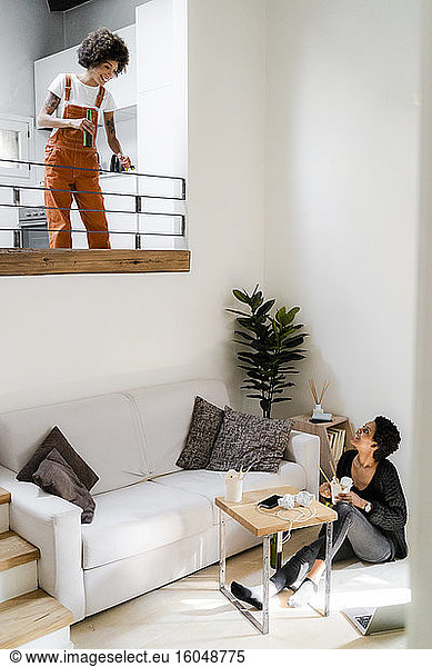 Two young women relaxing at home with Asian food and beer