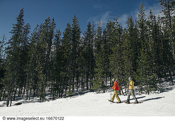 Two young women snow shoe on Mt. Hood on a sunny day.
