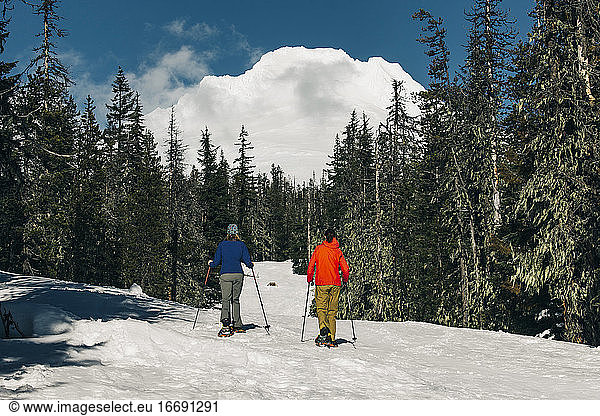 Two young women snowshoe on Mt. Hood on a sunny day.