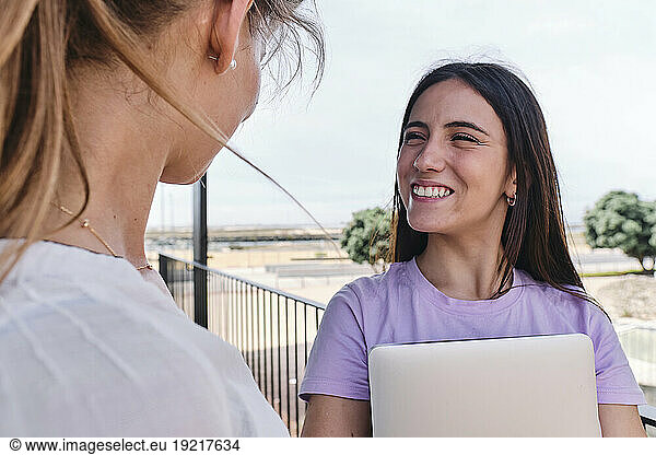 Two young women talking on balcony