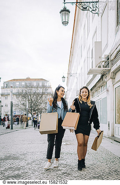 Two young women walking on the street with shopping bags  Lisbon  Portugal
