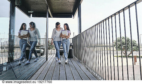 Two young women walking side by side on balcony