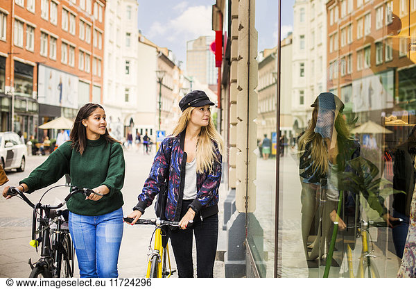 Two young women with bicycles looking at store window