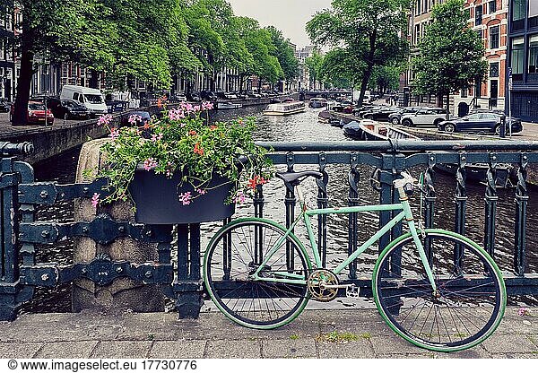Typical Amsterdam view  Amsterdam canal with boats and parked bicycles on a bridge with flowers. Amsterdam  Netherlands