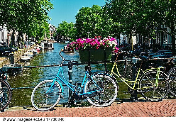 Typical Amsterdam view  Amsterdam canal with boats and parked bicycles on a bridge with flowers Amsterdam  Netherlands
