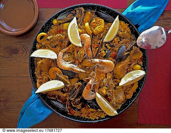 Typical paella pan on wooden table  Spanish rice dish  pan dish  paella pan  pan with Spanish national dish  prawns on paella  mussels in paella  national dish  region of Valencia  Spanish cuisine  Spanish recipes