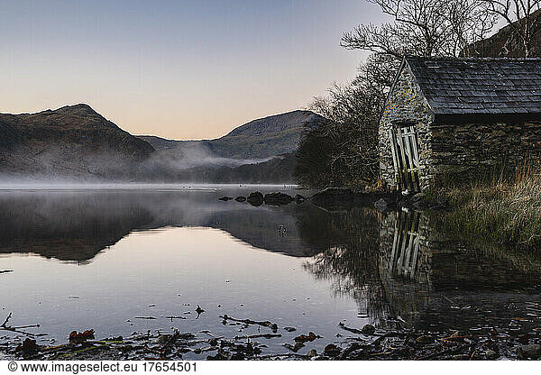 UK,  Wales,  Lakeshore hut at foggy dawn