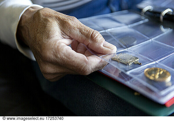 UK  East Sussex  Close-up of senior mans hand holding coin album
