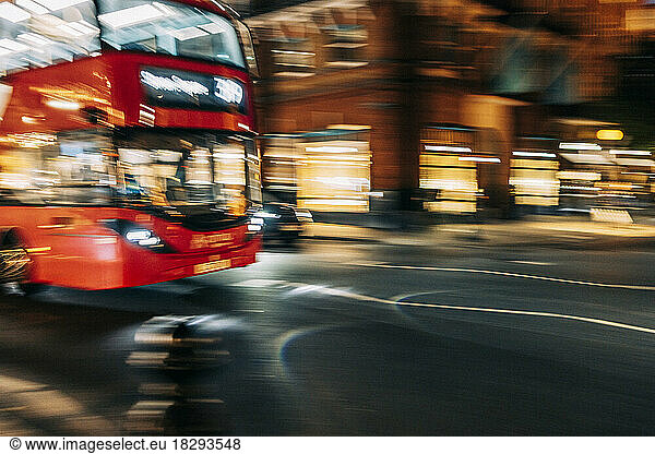 UK  England  London  Blurred motion of double-decker driving along city street at night