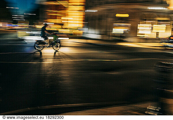 UK  England  London  Blurred motion of person riding motorcycle along city street at night