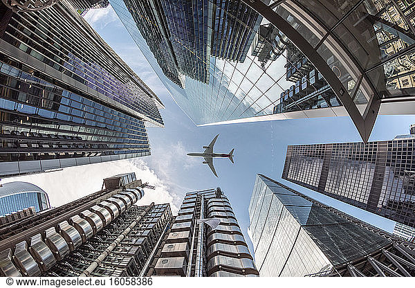UK  London  Flugzeug fliegt über moderne Wolkenkratzer an einem sonnigen Tag  Froschperspektive