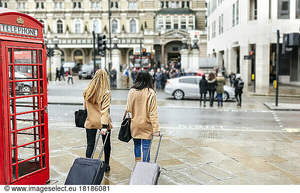 UK  London  Two friends exploring the city  arriving with trolley bags