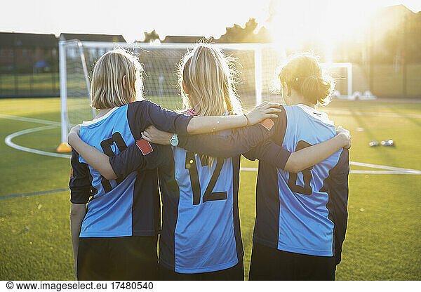 UK  Rear view of female soccer players (10-11  12-13) embracing in field