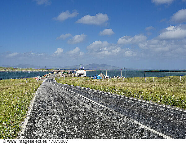 UK  Scotland  Empty asphalt road in Outer Hebrides with ferry in background