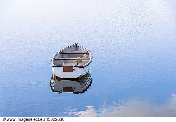 UK  Scotland  Empty rowboat floating in shiny lake