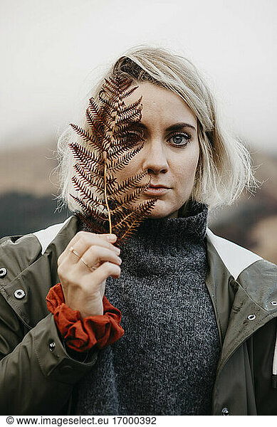 UK  Scotland  Highland  portrait of young woman holding fern