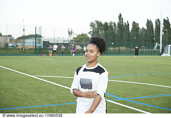 UK  Smiling female soccer player (12-13) in soccer field