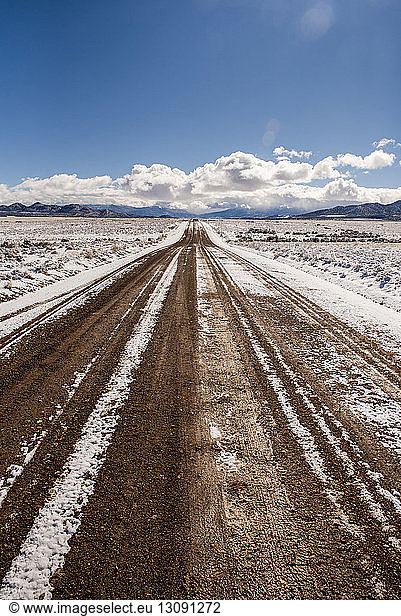 Unbefestigte Straße inmitten einer verschneiten Wüste gegen den Himmel im Winter