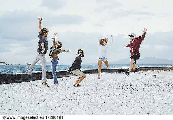 Unbekümmerte Freunde springen am Strand