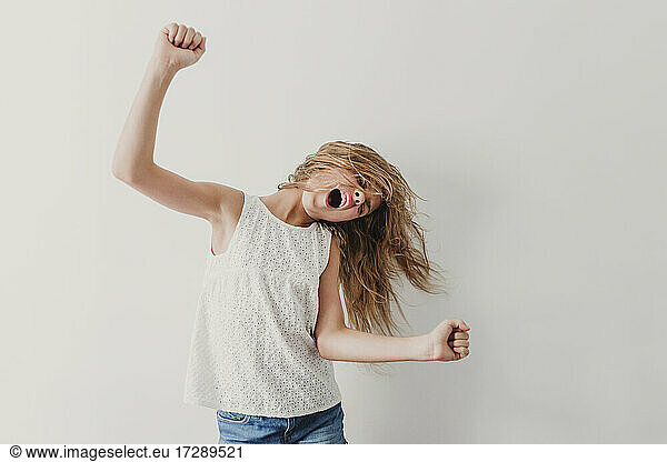 Unbekümmertes Mädchen tanzt vor einer Wand
