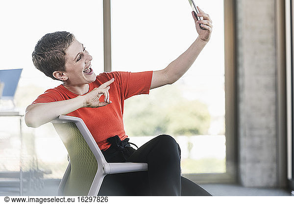 Unbeschwerte Geschäftsfrau mit Smartphone im Büro