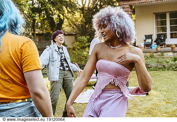 Unbeschwerte Transfrau tanzt mit LGBTQ-Freunden während einer Dinnerparty im Hinterhof