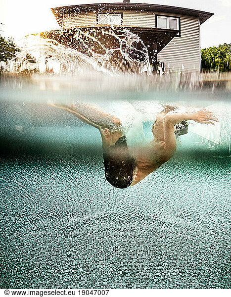 underwater view of a boy jumping and splashing in the pool