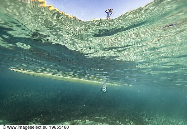 Underwater view of man paddleboarding