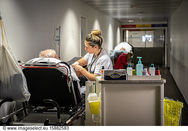 Une infirmières examine un patient dans un brancard.