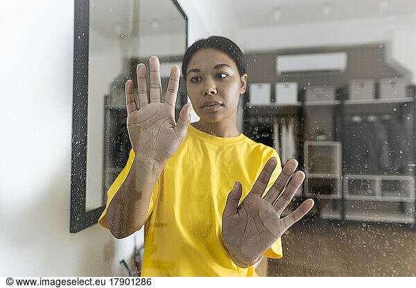 Unhappy woman touching confining glass pane