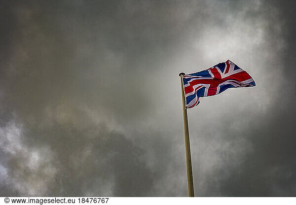 Union Jack flag waving below storm clouds