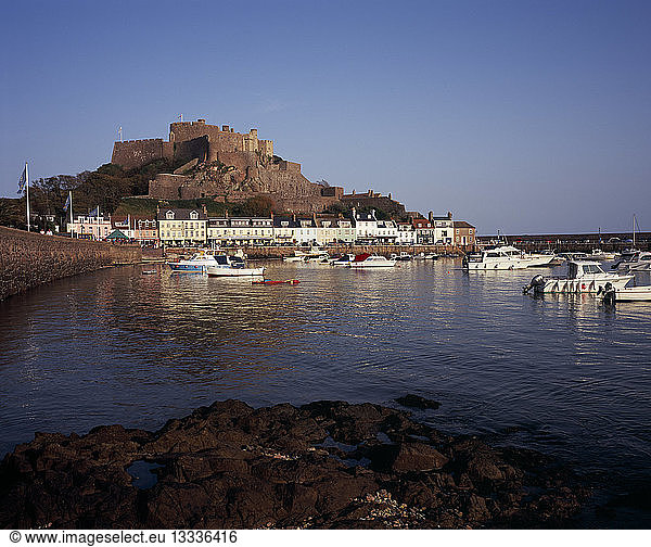 UNITED KINGDOM Channel Islands Jersey Grouville. Gorey Castle or Mont Orgueil set on hill overlooking village buildings and boats in harbour with the tide in. On the east coast.